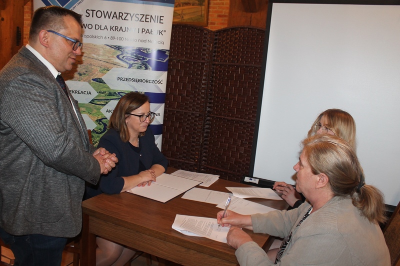 Stypendystka z mamą podpisują umowę w obecności prezes Zarządu.
